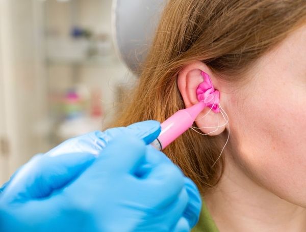 Eine Frau bekommt eine Masse ins Ohr gespritzt um eine Form zu erstellen